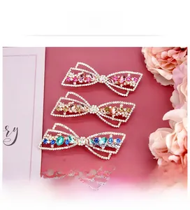 Trois barrettes à nœuds avec strass en rose, champagne et bleu paon en gros plan