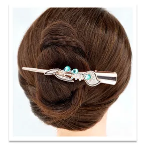 Detail of rose gold flower hair clip with green crystals on brown wavy hair