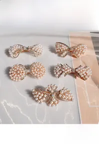 Détail de barrettes nœuds en perles avec centre en cristal sur tissu blanc texturé
