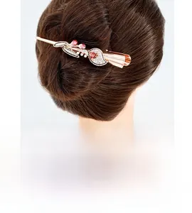 Detailed side view of rose gold leaf hair clip with white crystals and red gemstones