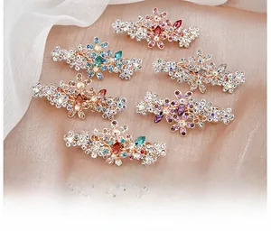 Détail de 6 pinces à cheveux à fleurs en strass colorés sur fond de tissu rose