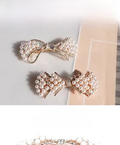 Détail des élégantes barrettes papillon dorées avec perles blanches et cristaux brillants