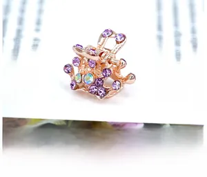Macro shot of rose gold crown hair claw clip with purple rhinestones on a white background