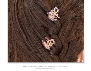 Detailed view of mini crown hair clips with purple crystals on braided hair