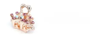 Close-up of a mini gold crown hair claw clip with pink crystals and rhinestones