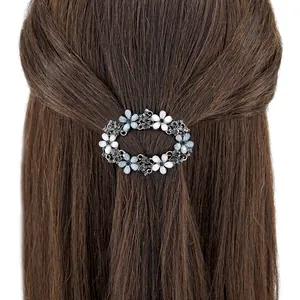 Barrette à fleurs évidées argentées et cristaux bleus sur cheveux bruns