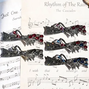 Retro gunmetal bow hair clips with rhinestones and teardrop gems on music sheet