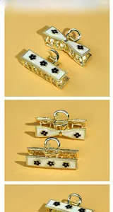 Detail view of gold alloy hair clips with white enamel and black floral bow design