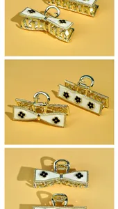 Detail of gold-plated alloy hair claw clips with white enamel and black clover patterns
