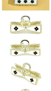 Detail view of gold metal hair claw clip with bow shape and black clover pattern