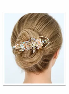 Détail d'une pince à cheveux de luxe dorée avec strass floraux sur un chignon