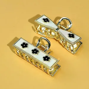 Golden alloy bow and rectangular hair claws with black clover motifs on white panels