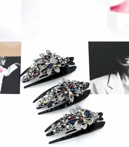 Detail of three large black hair claws with colorful rhinestone floral and leaf patterns