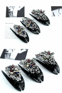 Detail of floral butterfly rhinestones on black duckbill clips set against a white background