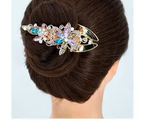 Détail de pince à cheveux florale avec cristaux violets et bleus sur base dorée