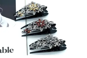 Detail of three vintage floral hair claws with rhinestones in red, gold, and grey colors