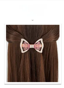 Détail d'une grande pince à cheveux avec strass roses et blancs en forme de nœud élégant