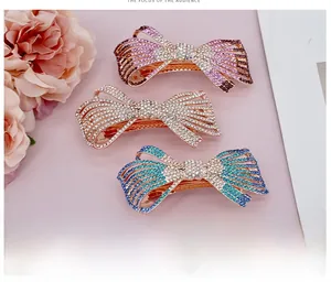 Détail de barrettes papillon en or rose ornées de strass dégradés roses, blancs et bleu-vert