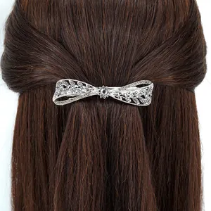 Barrette à cheveux nœud argenté avec strass foncés et design filigrane sur cheveux bruns