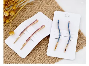Dettaglio di fermagli dorati con strass rosa e blu su uno sfondo intrecciato