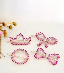 Detail view of rose gold hair clips with pink rhinestones in crown and bow shapes