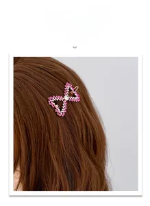 Champagne gold bow hair clip with pink rhinestones on a model with long wavy brown hair