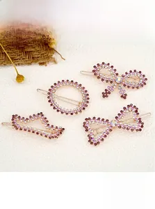 Detailed view of four golden hair clips featuring purple and white rhinestones in various shapes
