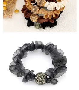 Detail of sheer mesh scrunchie with sparkling rhinestone sphere in black and neutral tones