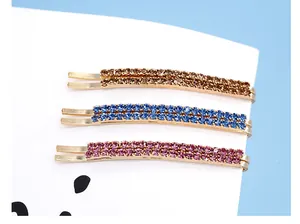 Dettaglio di tre forcine luccicanti con strass nei colori champagne blu e viola