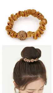 Detail of champagne gold satin scrunchie with a sparkling rhinestone ball ornament