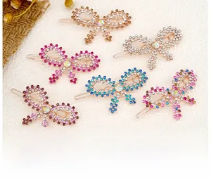 Detail of colorful rhinestone bow hair clips in rose gold setting on cream fabric