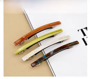 Détail de quatre barrettes à ressort en acétate coloris ambre, vert, blanc et motif écaille