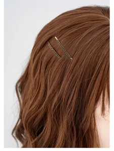 Dettaglio di due fermagli dorati con cristalli neri indossati su capelli castani