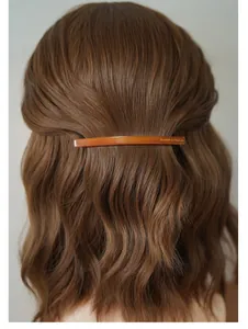 Détail de la barrette en écaille ambrée avec inscription dorée sur cheveux mi-attachés