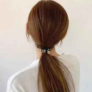 Élastique à cheveux noir avec anneau en strass et pendentif doré sur queue de cheval