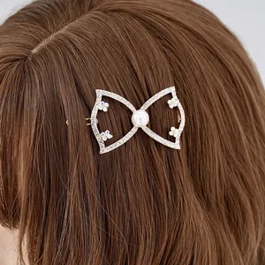 Pinza para el pelo con lazo de diamantes y perla sobre cabello castaño de cerca