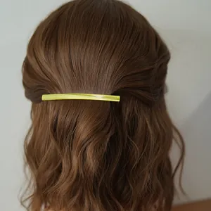 Barrette minimaliste en acétate vert citron sur des cheveux bruns ondulés