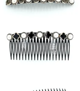 Detail of vintage hair comb with black clover motifs, white pearls, and gold metal edges