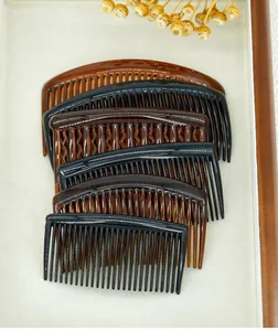 Detail of multi-color plastic hair side combs set on a natural wooden display tray