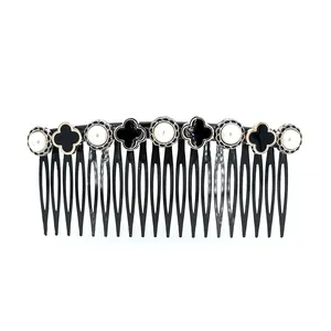 French vintage hair comb with white pearls and black clover accents on white backdrop
