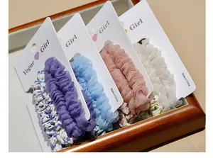 Detail of four pastel organza scrunchies in a wooden tray with floral patterns