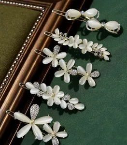 Detail of five cat-eye stone hair clips with white petals, bows and sparkling rhinestones