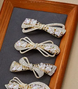 Detailed view of rhinestone bow hair clips with pearls on a premium display board