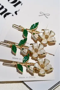 Detailed view of three floral hair clips with white enamel petals and gold alloy base