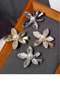 Detail view of four metallic flower hair clips with textured petals and center pearls