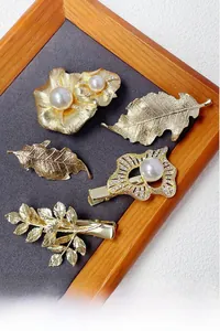 Macro detail of a 5-piece gold hair clip set featuring leaf and floral pearl designs