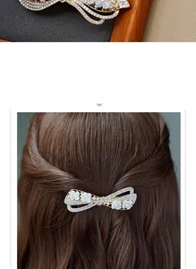 Detail of elegant gold-tone bow hair clip with white crystals and flowers on a model