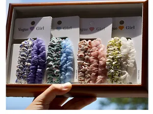Close-up of colorful floral and solid scrunchies set on white display card with textures