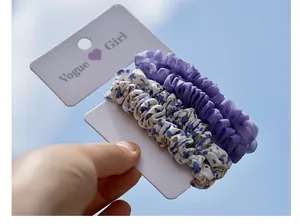 Three-piece floral and purple gauze scrunchie set shown against a blue sky background