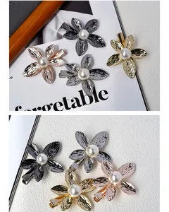 Detail of four metallic flower hair clips with pearls and brushed metal texture